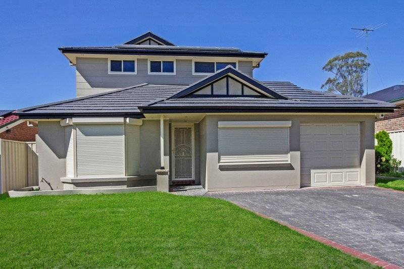 Modern two-story house with light-colored walls, large windows with shutters, a dark tiled roof, a single garage, and a well-maintained front lawn under a clear blue sky.