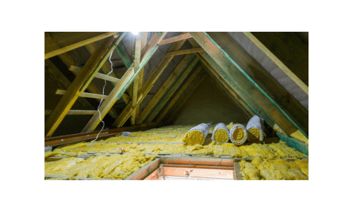 Insulation - Standard Inclusion Attic with wooden beams and insulation material covering the floor; several rolls of insulation are placed on top, and a small window or opening is visible at the bottom.